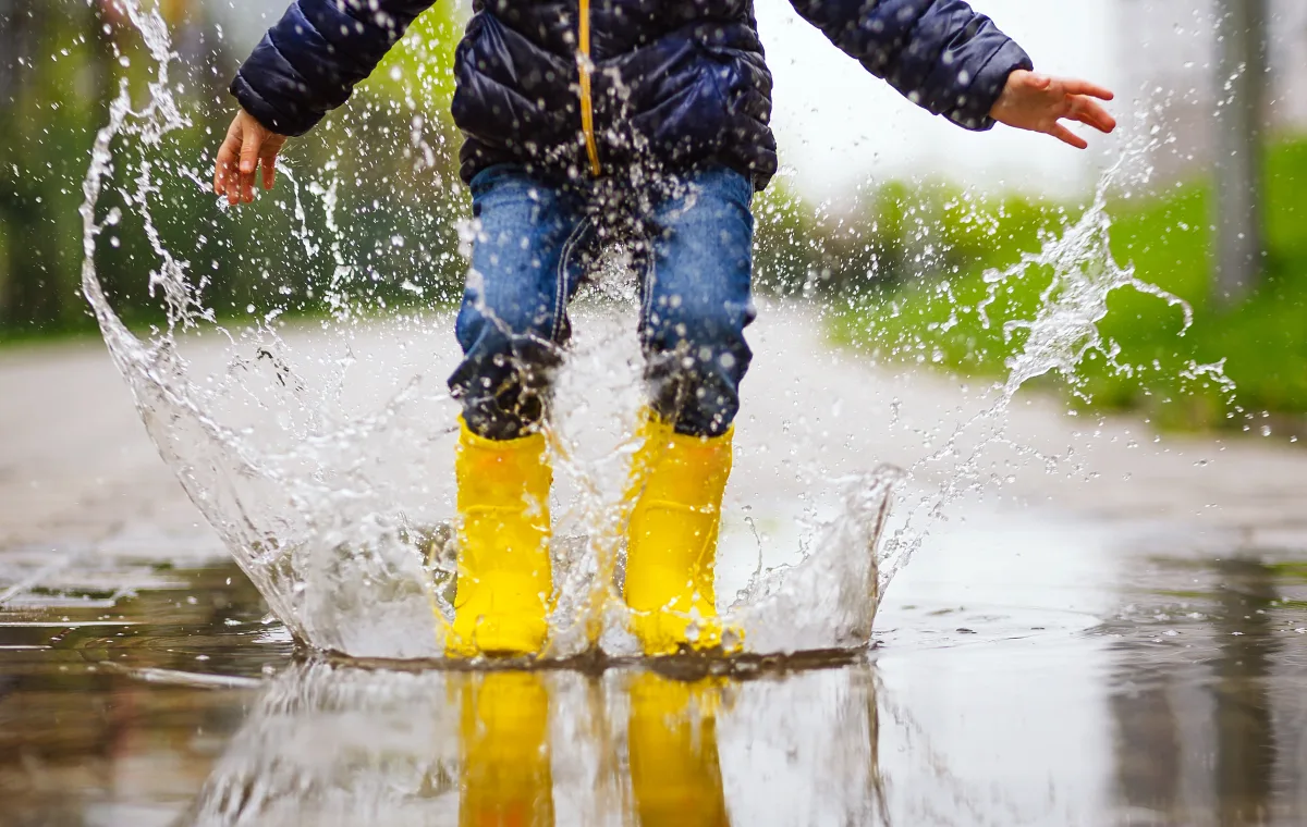 child jumping in puddle